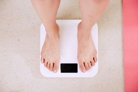 Person weighing themselves- lose weight without exercise